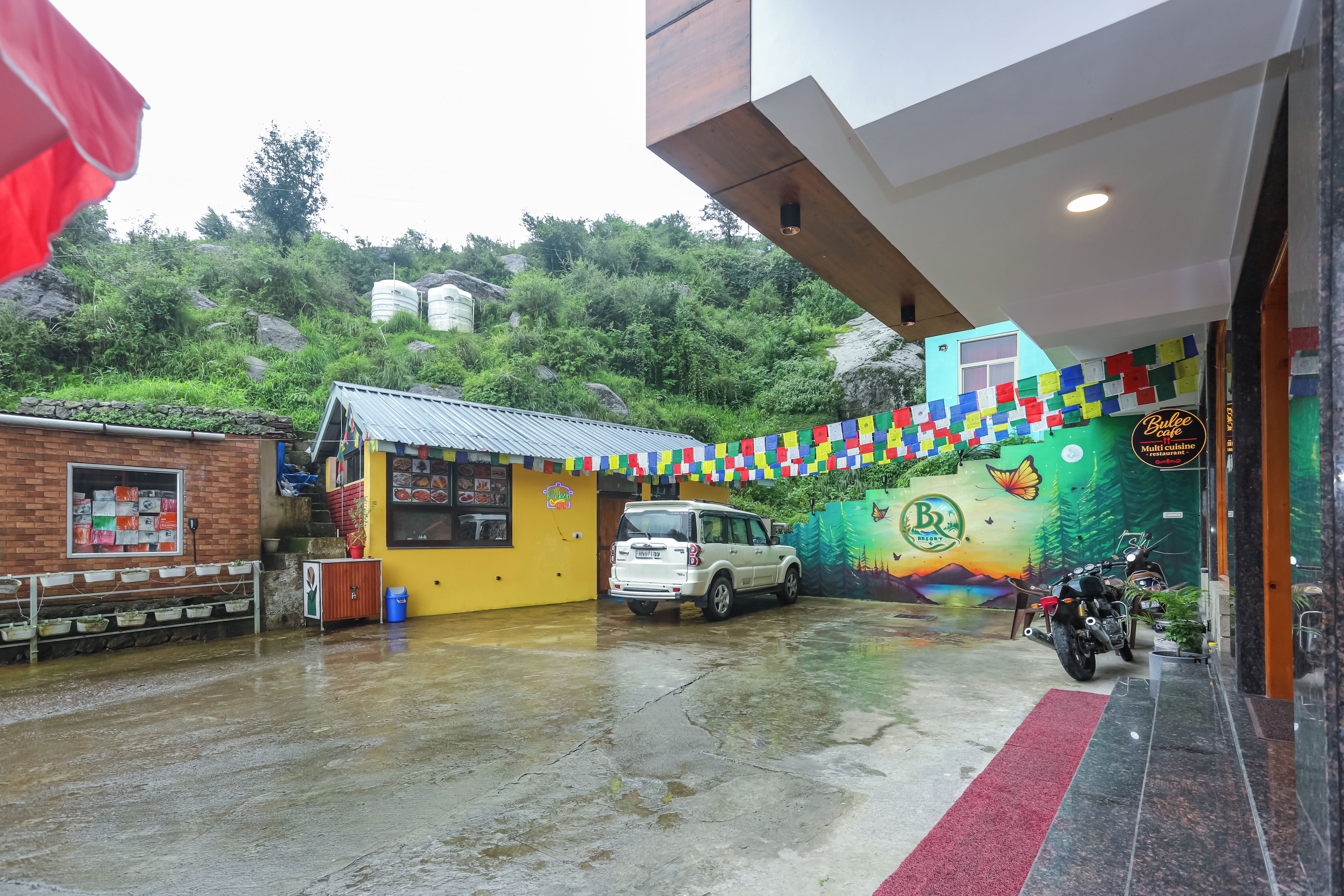 A building with a mural, a parked car, and a motorcycle.