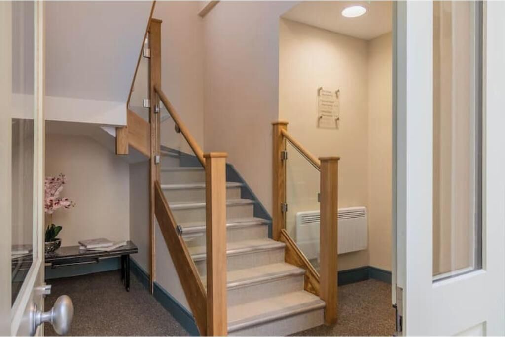 A staircase with wooden railings, carpeted steps, a radiator, and a door with a glass panel.