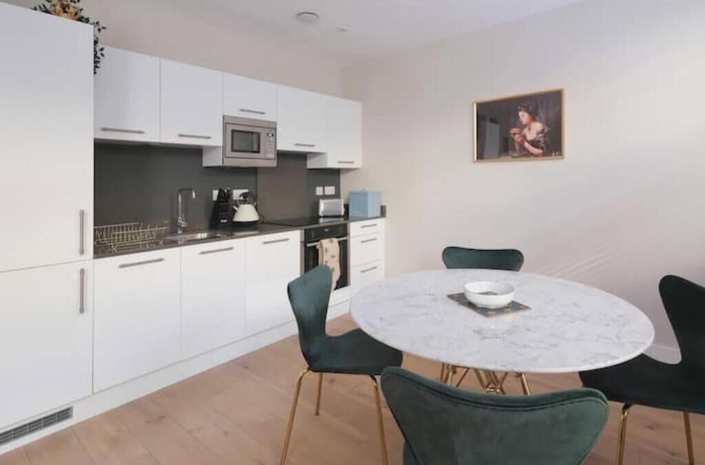 A modern kitchen with white cabinets, a microwave, and a round dining table with chairs.