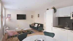 A modern living space with a dining area, a sofa, a TV, and a kitchen area. - Modern Two-Bed Apartment in Central Bath (Bath)