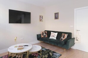 A living room with a sofa, a coffee table, a flat-screen TV, and a door. - Modern Two-Bed Apartment in Central Bath (Bath)