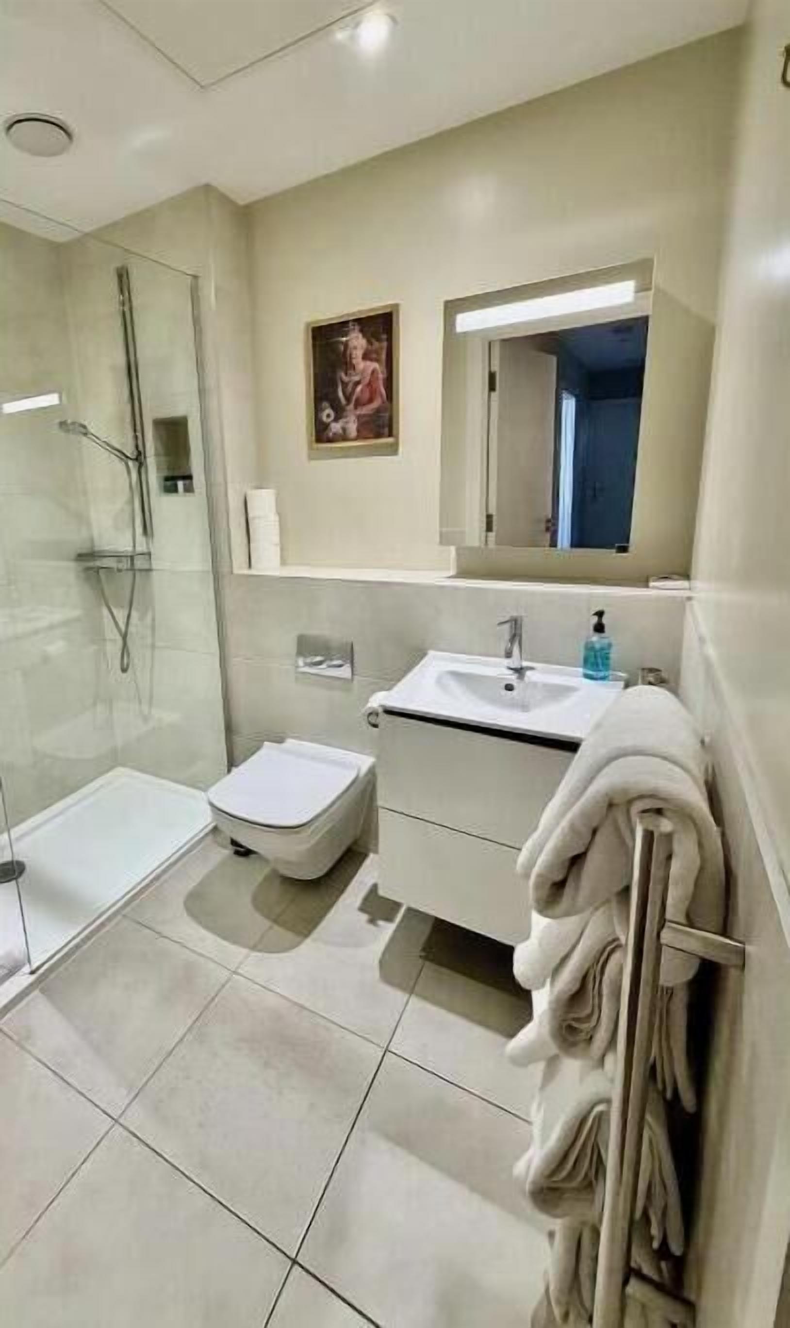 Ein modernes Badezimmer mit einer gläsernen Duschkabine, einem weißen Waschbecken und einem Handtuchhalter.