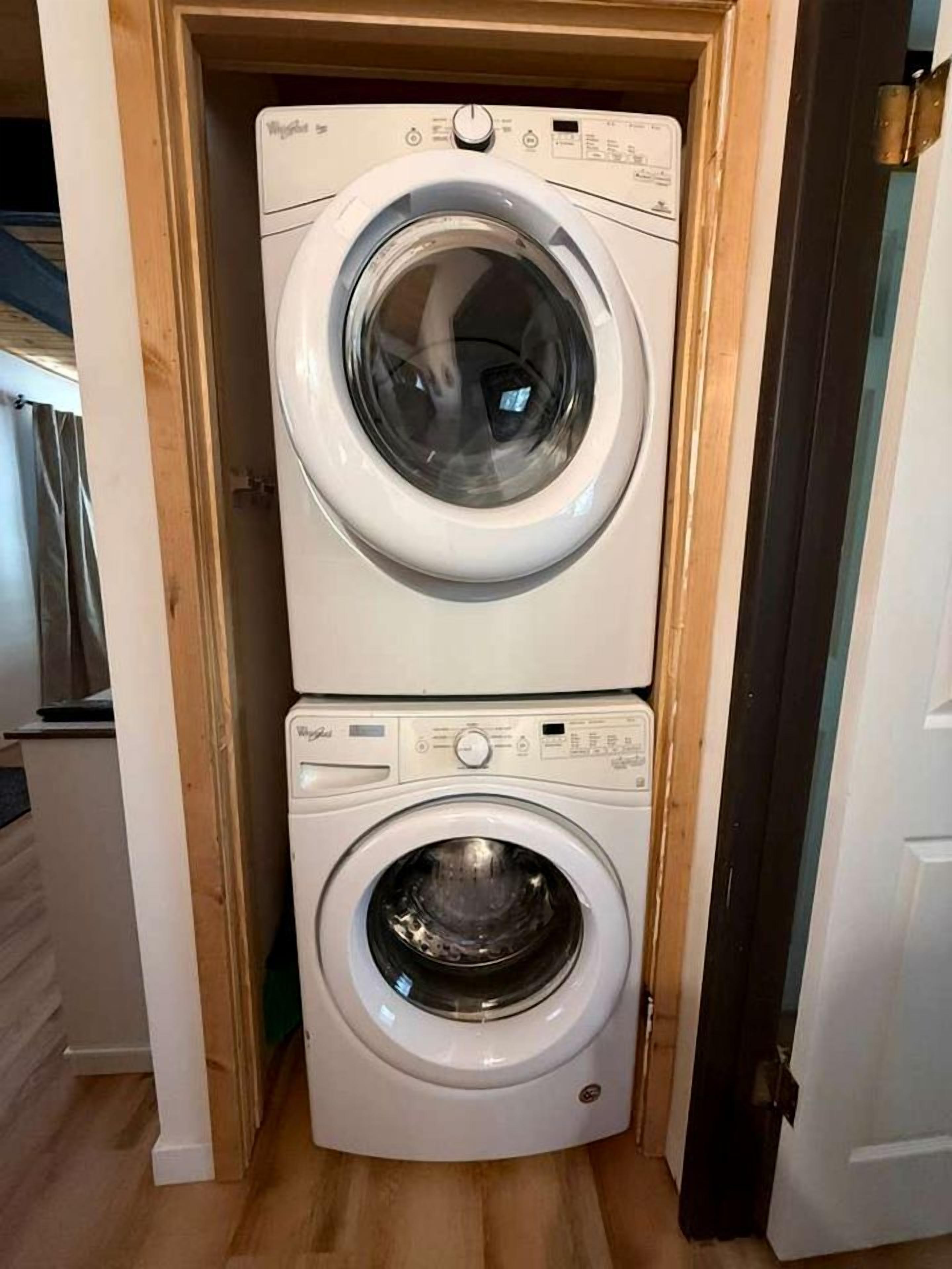 A stacked washer and dryer unit in a hallway.