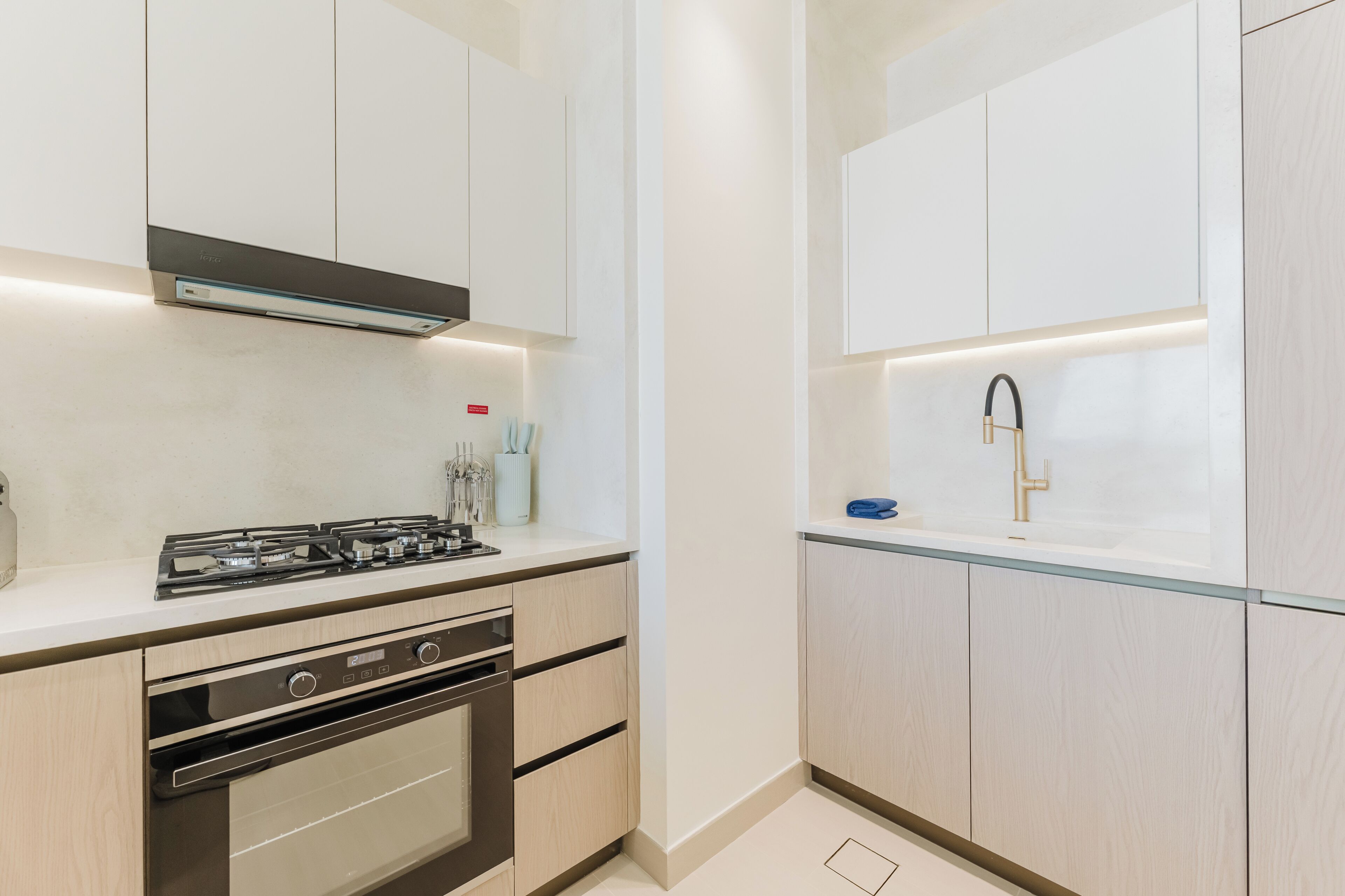 A modern kitchen with a gas stove, oven, and a built-in sink with a gold faucet.