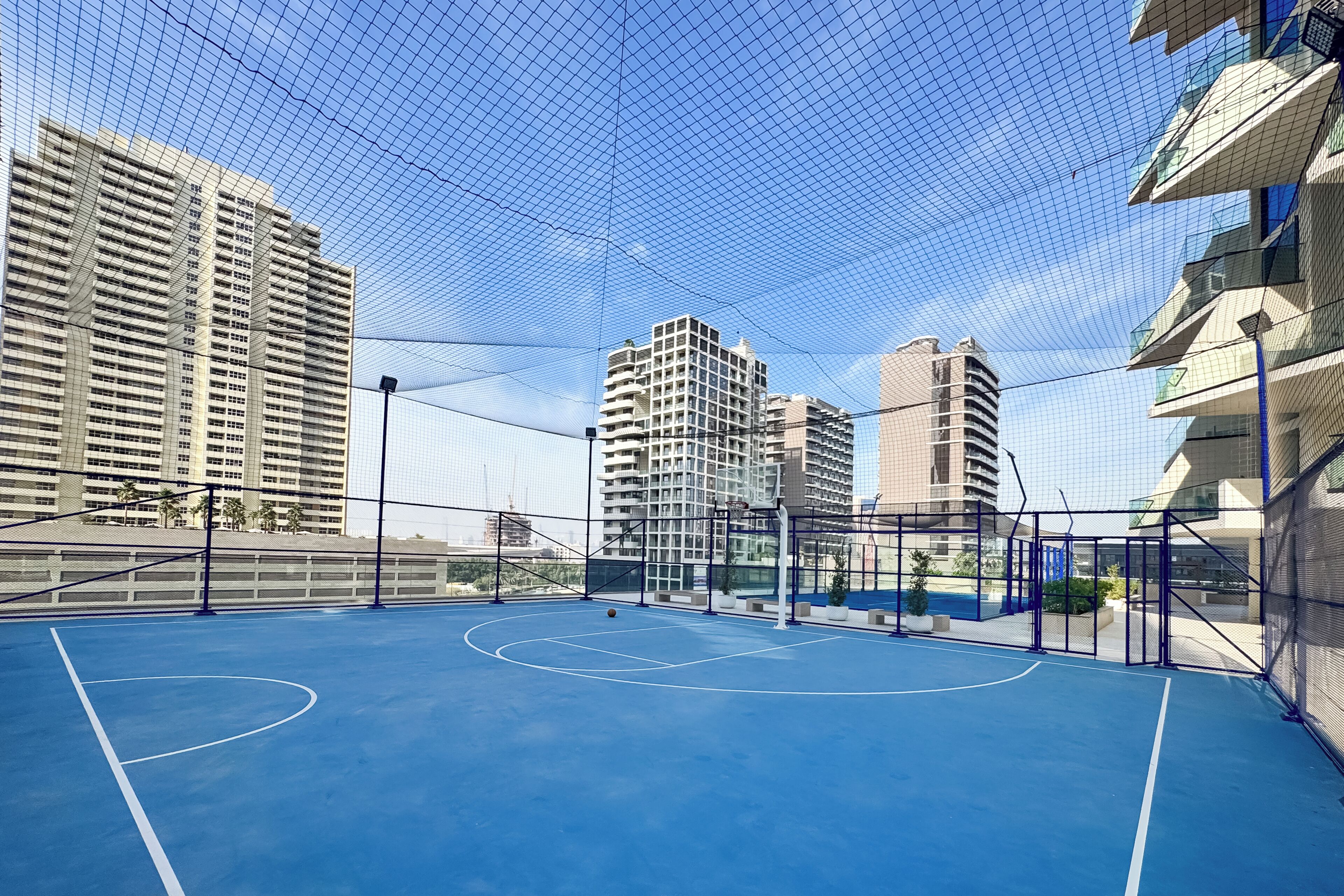 Een basketbalveld buiten, omringd door hoogbouw.
