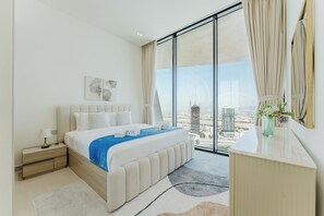 A modern hotel room with a large bed, a nightstand, a dresser, and a city view. - PVH - Binghatti Royale 1BR Private Pool (Dubai)