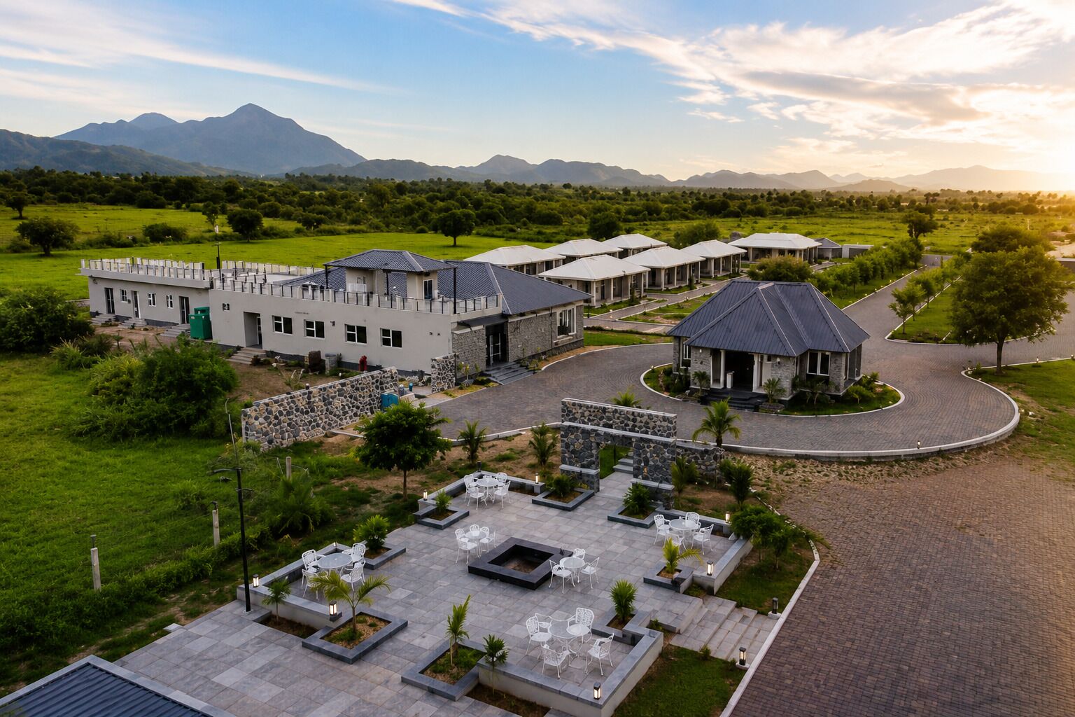 A resort with multiple buildings, outdoor seating areas, and a mountainous backdrop.