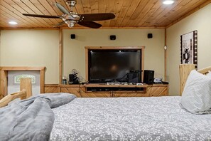 A bedroom with a bed, a ceiling fan, a television, and a wooden headboard. - Luxury Log Cabin Escape with Hot Tub, Decks & Family Fun Spaces in Sevierville, Tennessee (Sevierville)