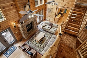 A spacious living area with a stone fireplace, a sofa set, and a dining table. - Luxury Log Cabin Escape with Hot Tub, Decks & Family Fun Spaces in Sevierville, Tennessee (Sevierville)