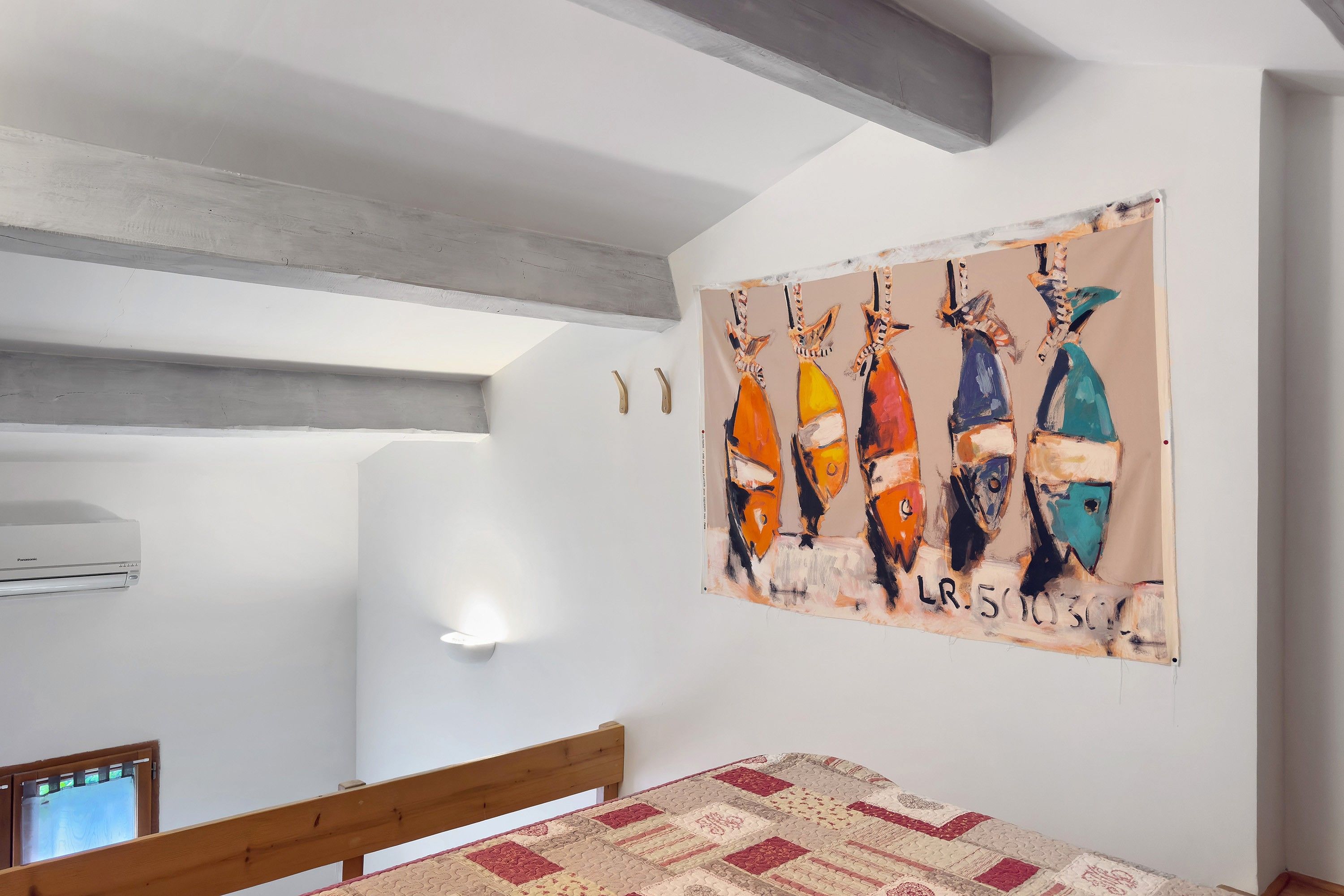 Een slaapkamer met een bed, een wandairconditioner en een schilderij.