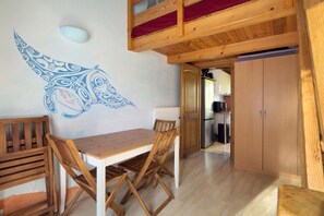 A wooden dining table with chairs, a kitchen area with appliances, and a red ceiling. - Holiday Home 'Bergerie Des Estelles' with Mountain View, Wi-Fi and Air Conditioning (Auriol)