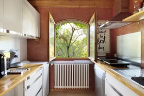 A compact kitchen with a window view, a built-in stove, and a coffee maker. - Holiday Home 'Bergerie Des Estelles' with Mountain View, Wi-Fi and Air Conditioning (Auriol)