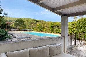A covered outdoor area with a swimming pool, lounge chairs, and a view of a hillside. - Holiday Home 'Bergerie Des Estelles' with Mountain View, Wi-Fi and Air Conditioning (Auriol)