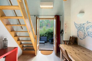 Een kamer met een houten trap, een eettafel en uitzicht op het landschap.