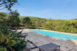 A swimming pool with a stone deck and lounge chairs, surrounded by lush greenery and hills in the background. - Holiday Home 'Bergerie Des Estelles' with Mountain View, Wi-Fi and Air Conditioning (Auriol)