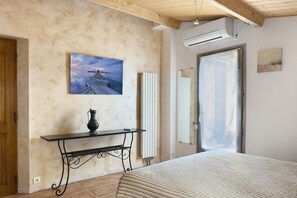 Een slaapkamer met een bed, een schilderij, een radiator en een deur.