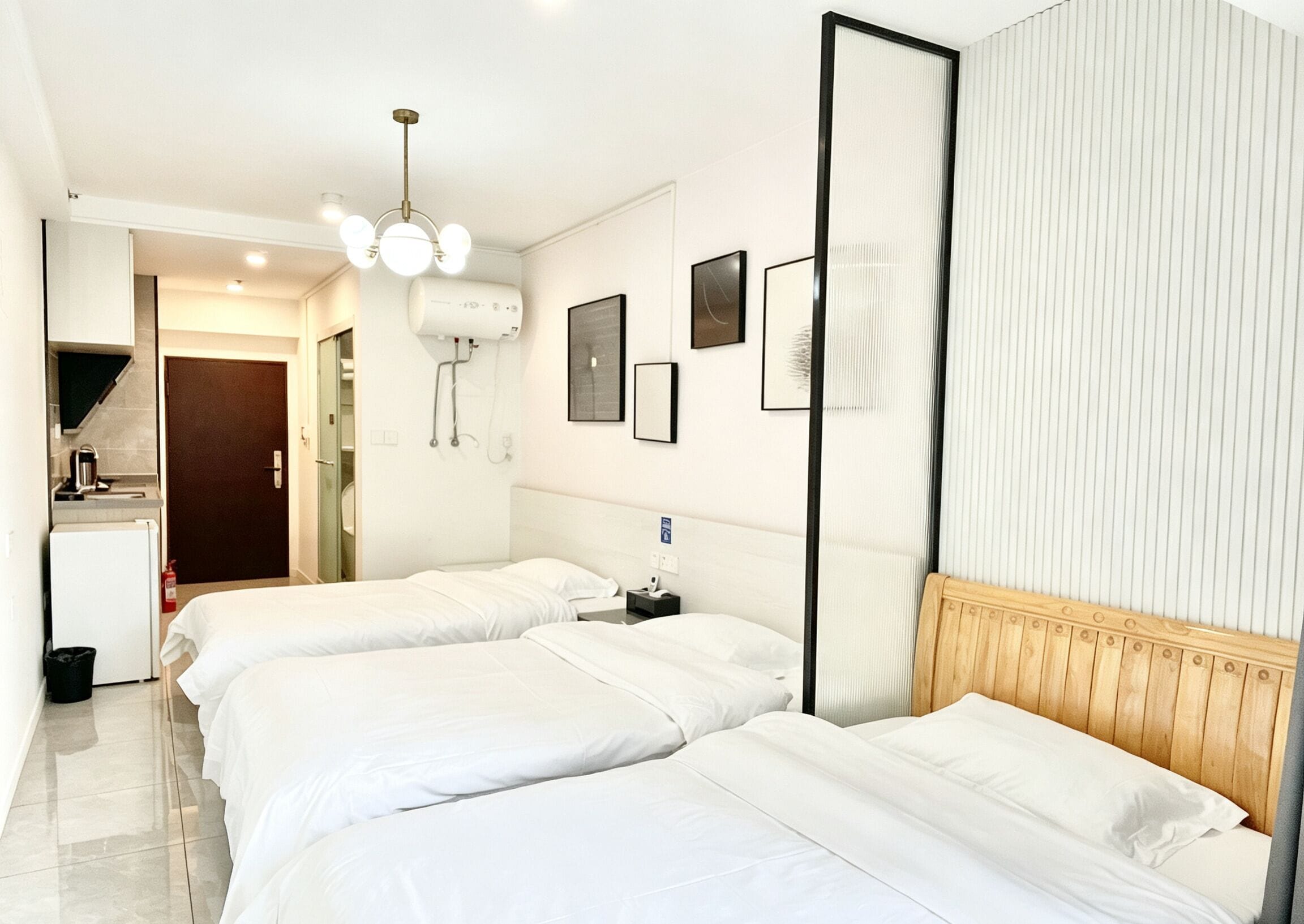 Quarto de hotel com duas camas, cozinha compacta, banheiro e um espelho grande.
