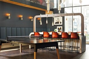 Ein Tischtennis-Tisch, eine Sitzecke und große Fenster in einem modernen Innenraum.