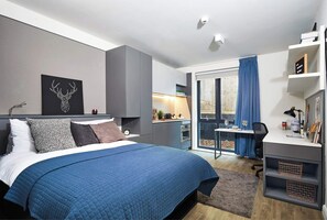 A modern bedroom with a bed, a desk, and a view of the outdoors. - Portswood House (Southampton)