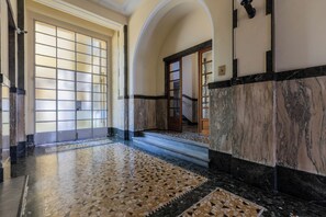 A hallway with a tiled floor, a staircase, and a door with frosted glass panels. - Galliari Comfort Home by Wonderful Italy (Torino)