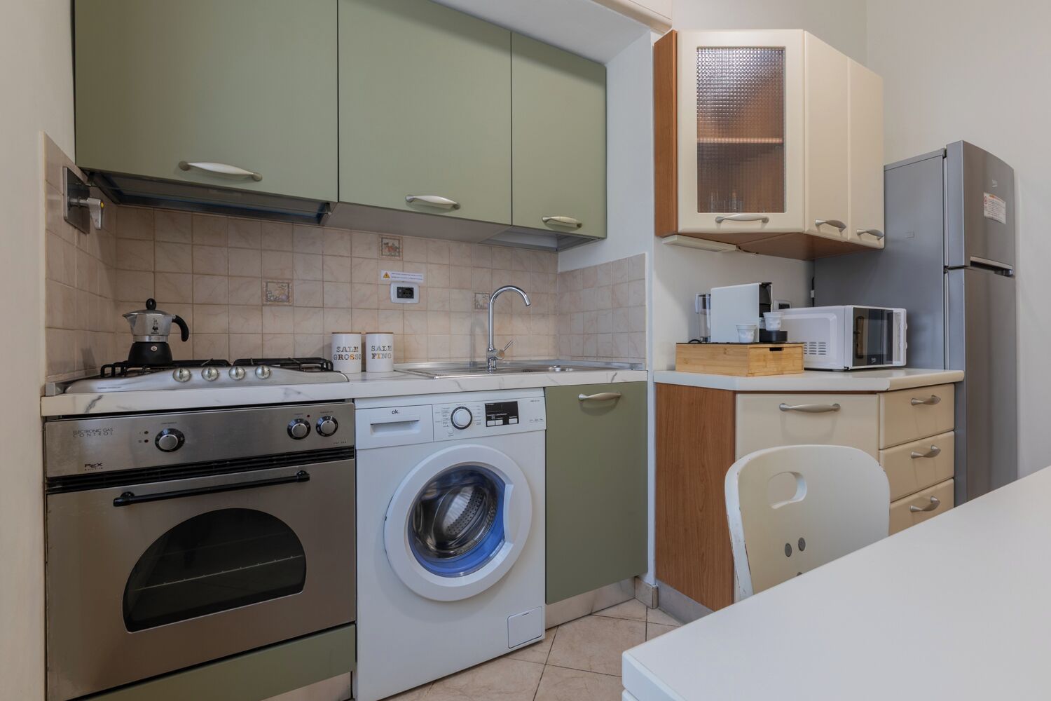 A compact kitchen with a stove, washing machine, microwave, and a sink.