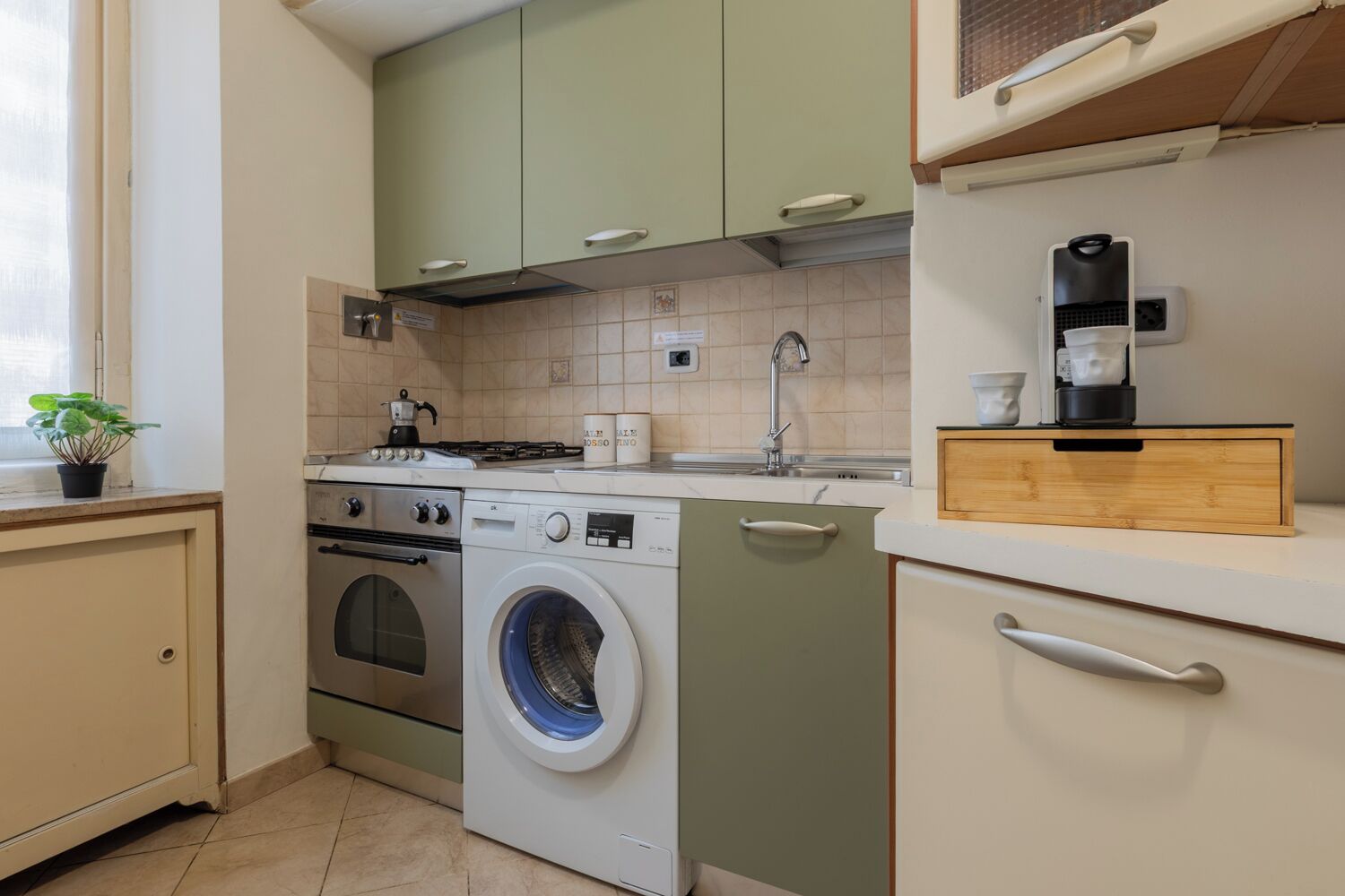 A compact kitchen with a washing machine, stove, and sink.