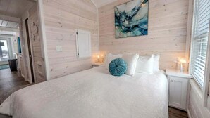 Um quarto com uma cama grande, um quadro na parede e uma janela com persianas.