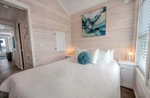Un dormitorio con una cama grande, un cuadro en la pared y una ventana con persianas.