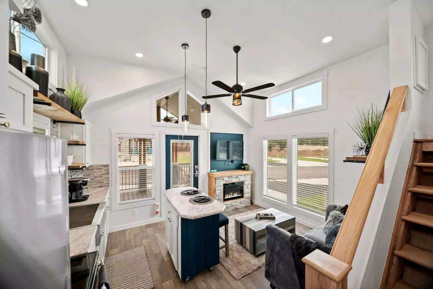 A modern kitchen with a stone island, a built-in oven, and a ceiling fan.