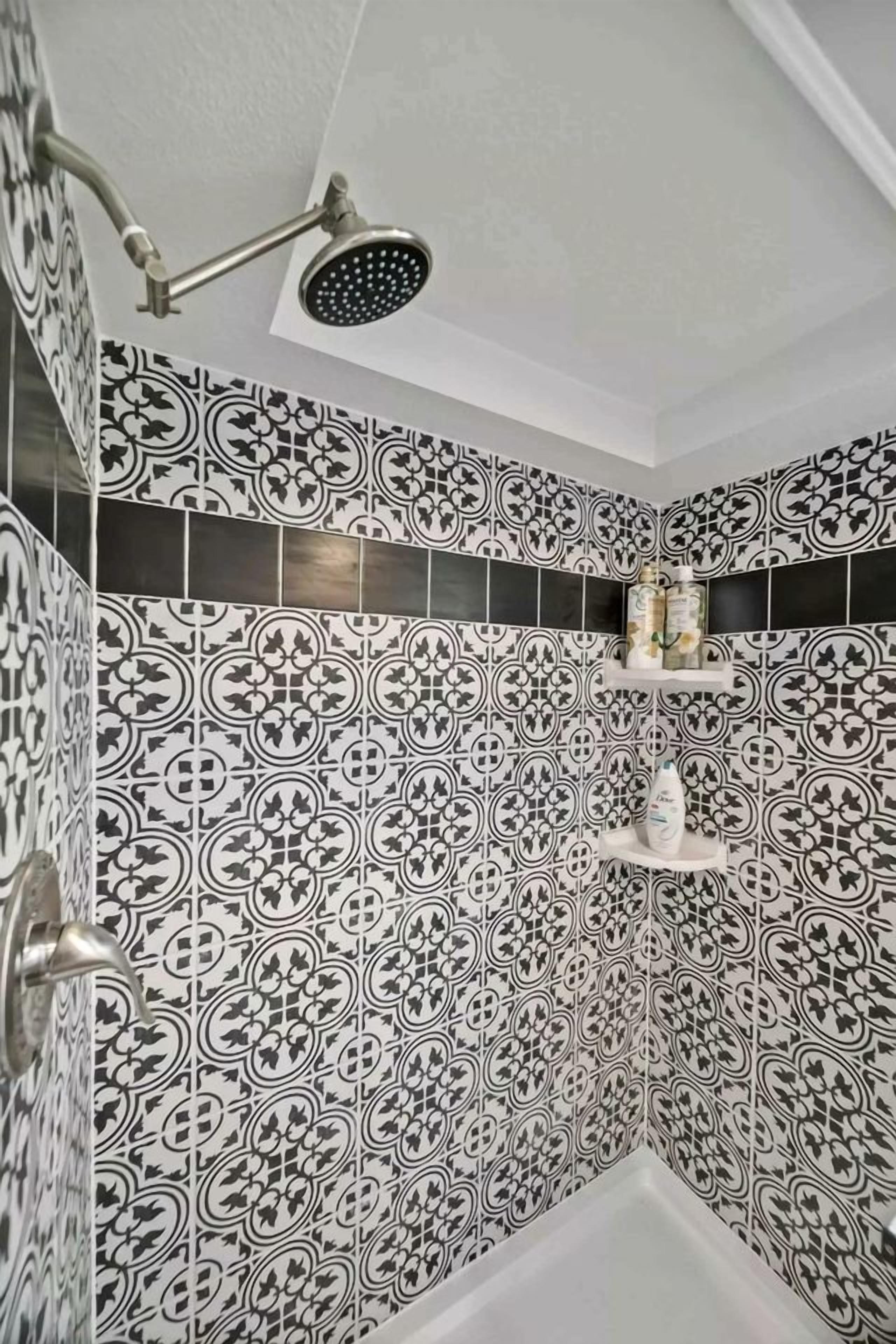 A bathroom with patterned tiles, a shower, and a shelf with toiletries.