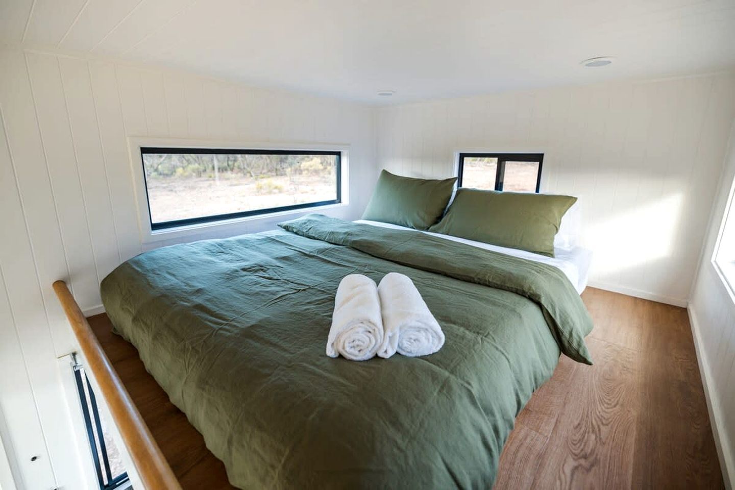 Un dormitorio con una cama grande, dos almohadas, una ventana y un par de toallas.