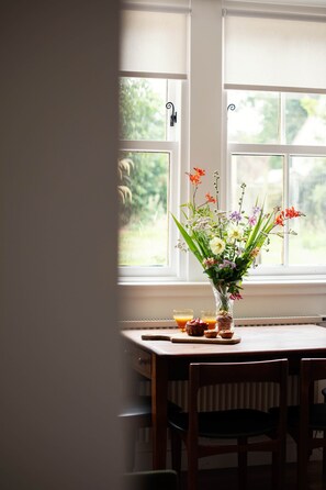 A dining table with a vase of flowers and two glasses of orange juice.
