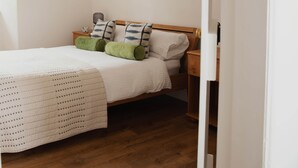 A bedroom with a wooden bed, white bedding, and green pillows.