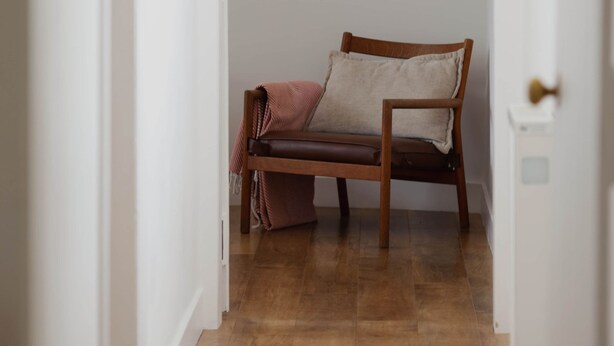 A narrow hallway with a wooden bench and a door on the right.