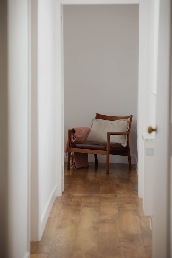 A narrow hallway with a wooden bench and a door on the right.