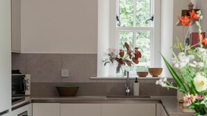 A modern kitchen with a window, a sink, and a dining area with a table and chairs.