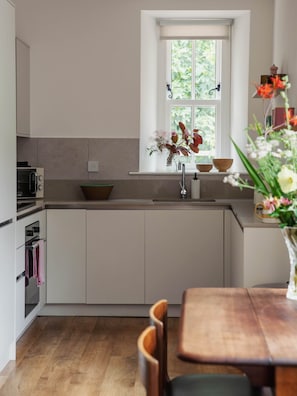 A modern kitchen with a window, a sink, and a dining area with a table and chairs.