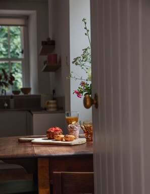 Een houten tafel met gebak en een glas sap in een keuken.
