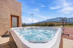 A hot tub with a mountain view, a basketball hoop, and a tall antenna.