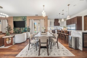 A modern kitchen with a marble countertop, stainless steel appliances, and pendant lighting.