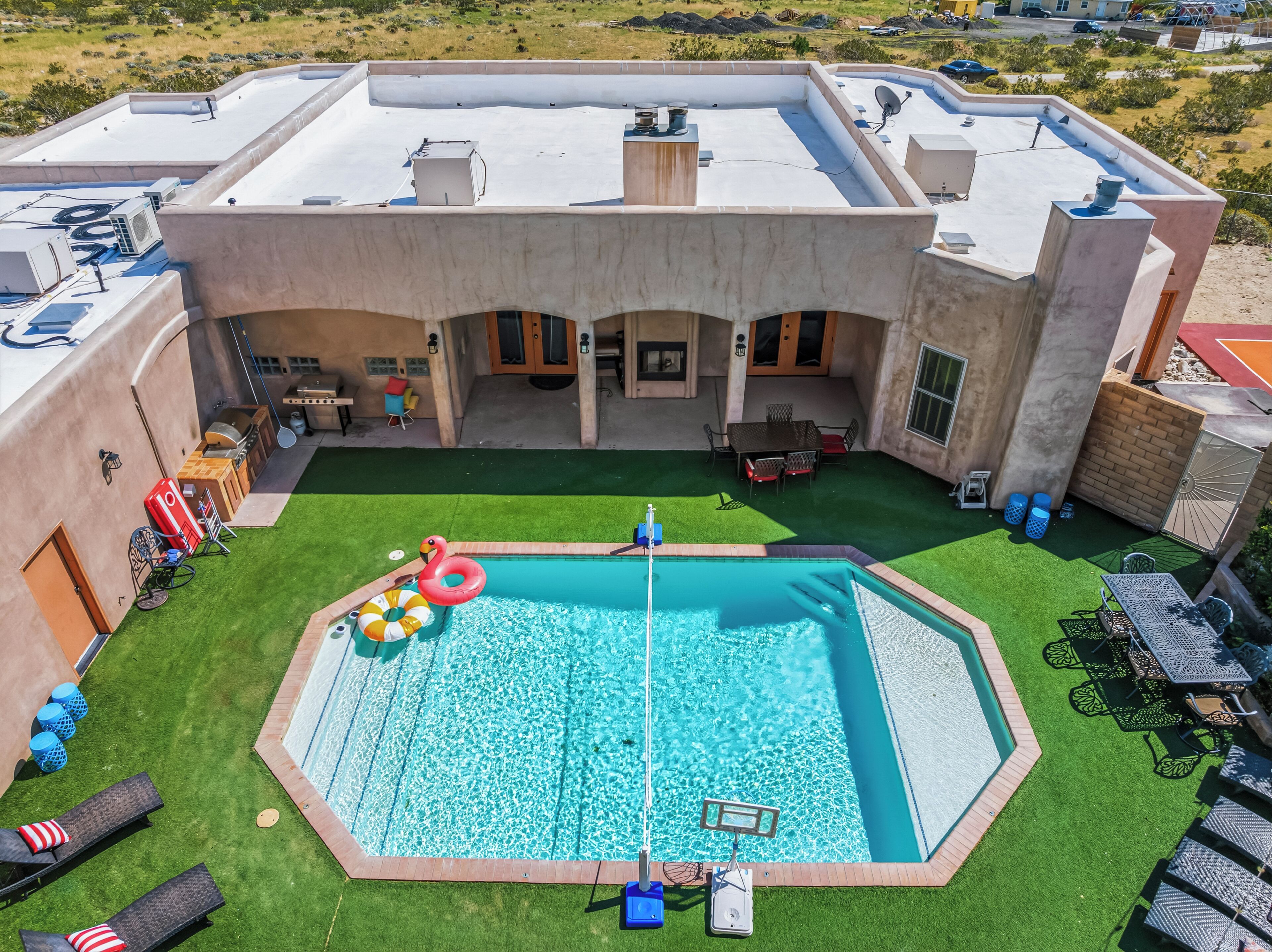 A rooftop pool with a diving board, surrounded by artificial grass, and a patio area with outdoor furniture.