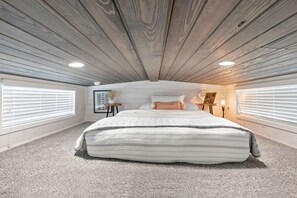 Een slaapkamer met een groot bed, twee nachtkastjes en een raam met jaloezieën.