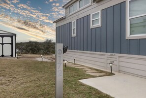 A modern building with a grey exterior, a clear sky, and a well-maintained lawn. - Elegant Tiny Home Retreat with Resort Amenities Near Fredericksburg, TX (Fredericksburg)