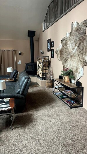 A living room with a fireplace, a large wall-mounted sculpture, and a bookshelf. - Charming Cabin Escape with Hot Tub & Wraparound Porch in McCall, Idaho (McCall)