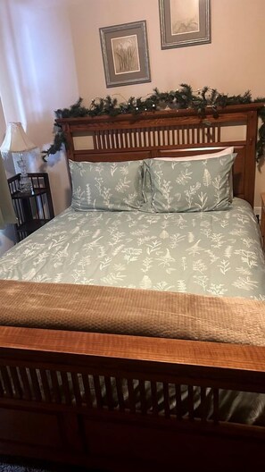 A bed with a wooden headboard, a floral patterned bedspread, and a decorative garland above it. - Charming Cabin Escape with Hot Tub & Wraparound Porch in McCall, Idaho (McCall)