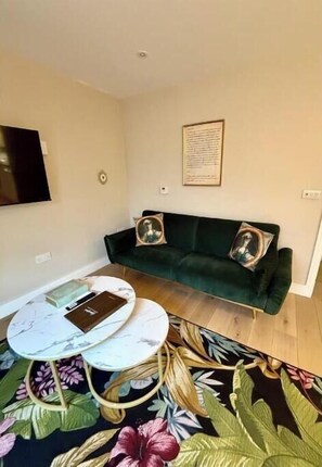 A living room with a green sofa, two armchairs, a round coffee table, and a floral rug. - Stylish One-Bed Apartment in Central Bath Near Train Station & Top Attractions (Bath)