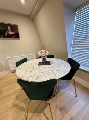 A round table with chairs, a vase with flowers, and a framed picture on the wall. - Stylish One-Bed Apartment in Central Bath Near Train Station & Top Attractions (Bath)