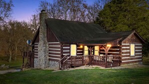 A log cabin with a stone chimney, wooden porch, and a small deck. - Spacious Riverfront Cabin with Hot Tub Near Shenandoah River, Maurertown, Virginia (Maurertown)