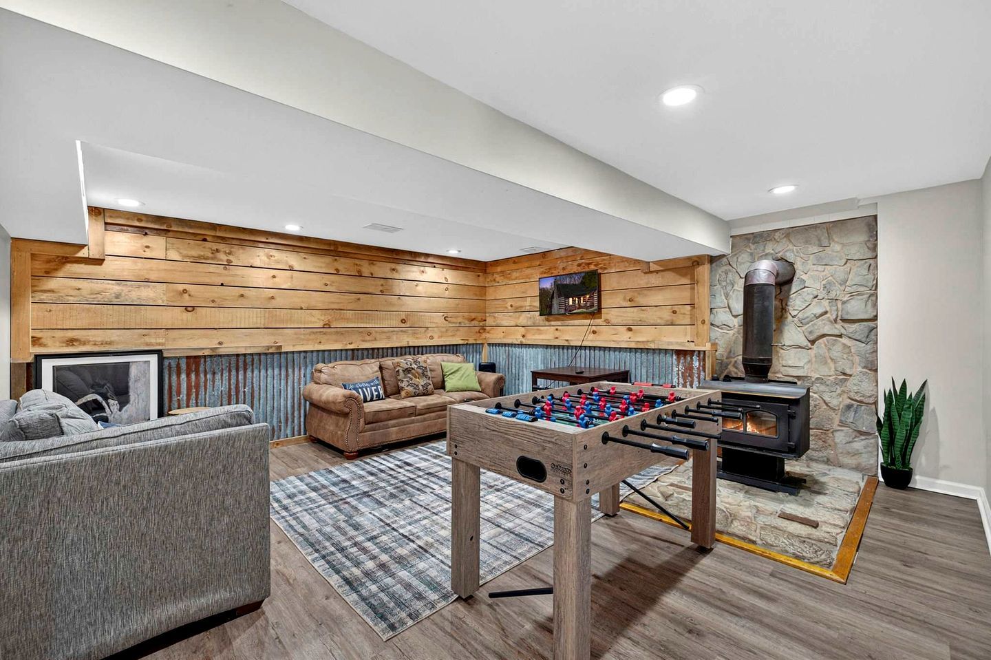 A cozy living room with a sofa, a foosball table, and a stone fireplace.