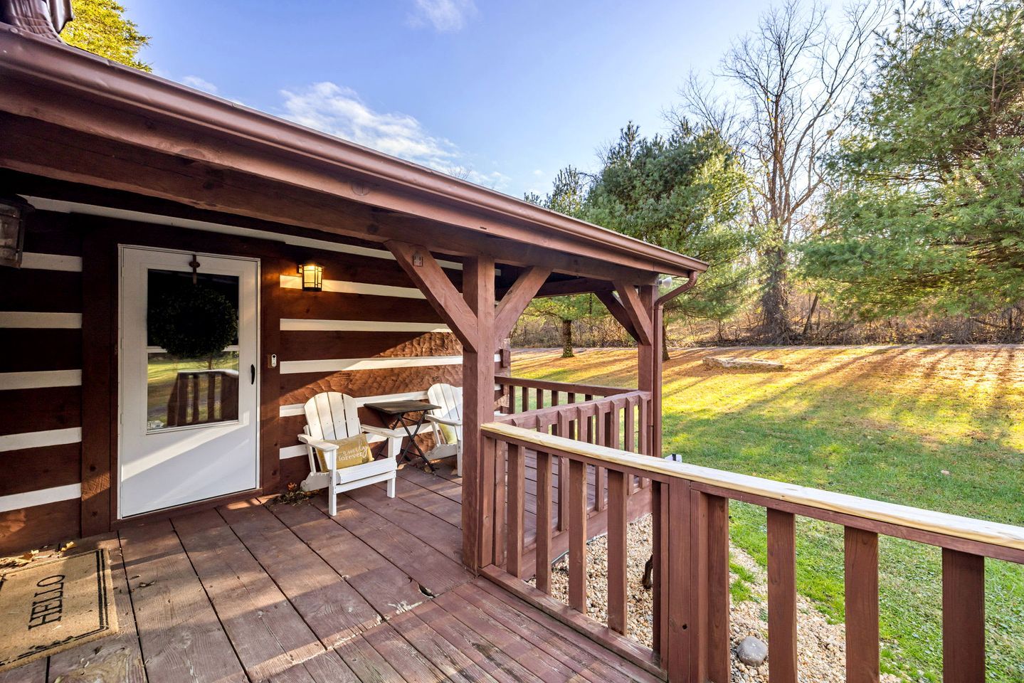 Eine Holzterrasse mit überdachter Sitzgelegenheit und einer Tür zu einem Raum.